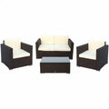 The image shows a set of garden furniture featuring a modern design. The set includes two single armchairs, a double-seater sofa, and a rectangular coffee table. All pieces are constructed with a dark brown wicker finish. The seating comes with cream-colored cushions, providing a sleek contrast to the dark frames. The coffee table features a glass top. The furniture is arranged in a clean, product-focused layout suitable for promotional purposes.