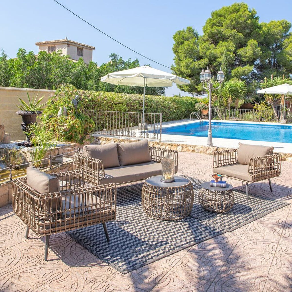 The 2-seater sofa placed on a spacious outdoor patio by a pool. The view includes lush greenery, a house in the background, and matching outdoor furniture, suggesting a comfortable and stylish outdoor living space.