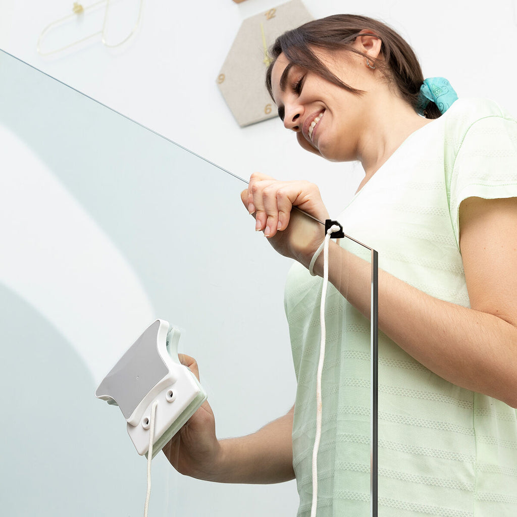 Person using the Magnetic Window Cleaner at a higher position, holding it steadily as it cleans the glass surface.