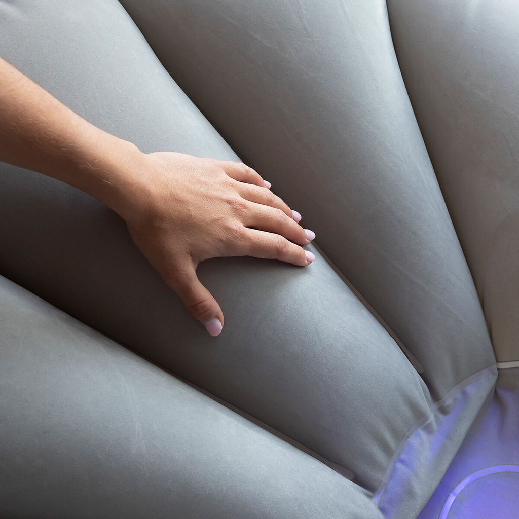 A close-up of a hand on the gray fabric of the chair, illustrating the soft and comfortable texture.