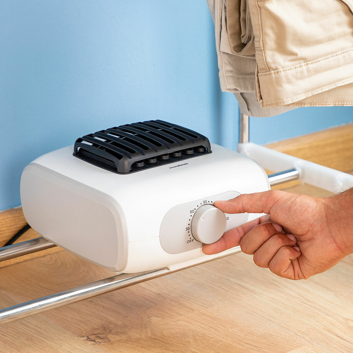 Close-up of the white electric component at the base of the dryer frame, featuring a dial to adjust settings. A hand is shown interacting with the control dial.