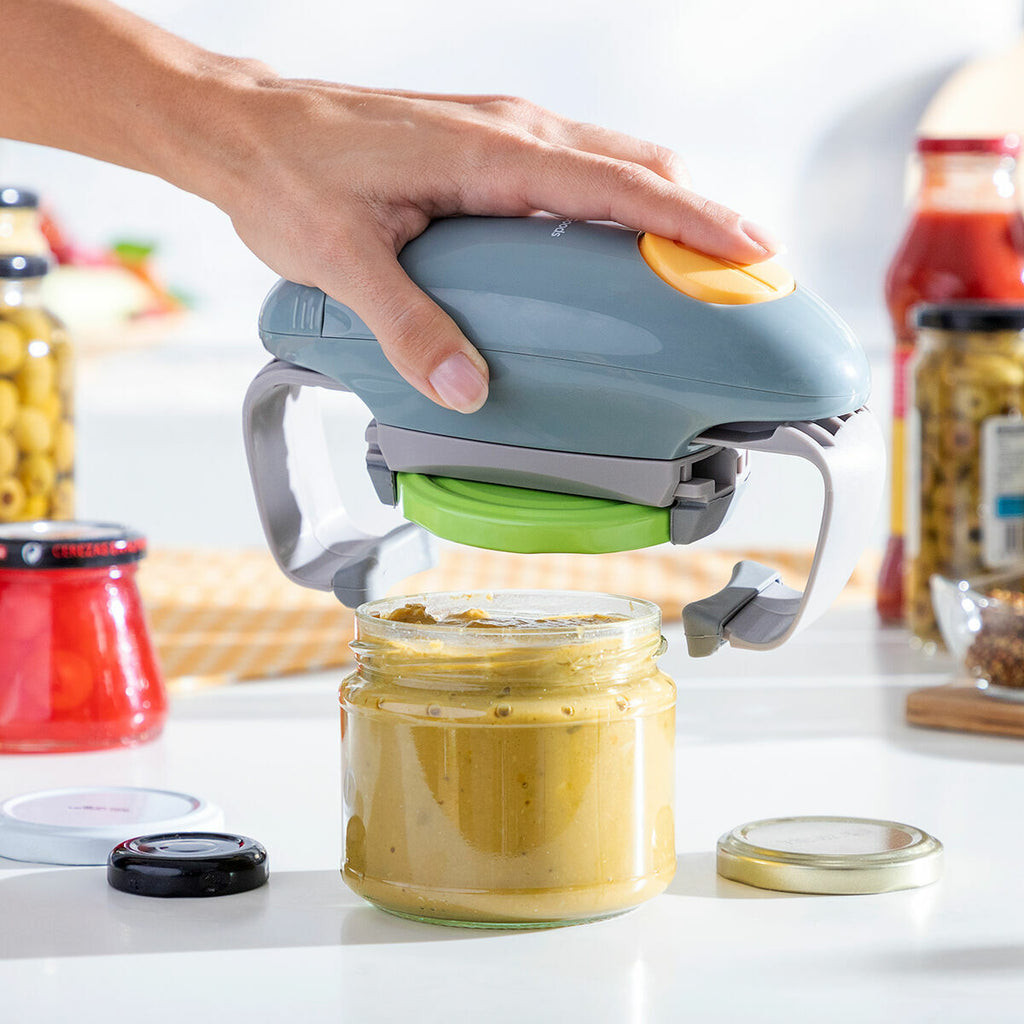 The Electric Jar Opener Lloucan InnovaGoods is shown being lifted from a jar with a green lid, the lid successfully removed, emphasizing the product’s effectiveness.