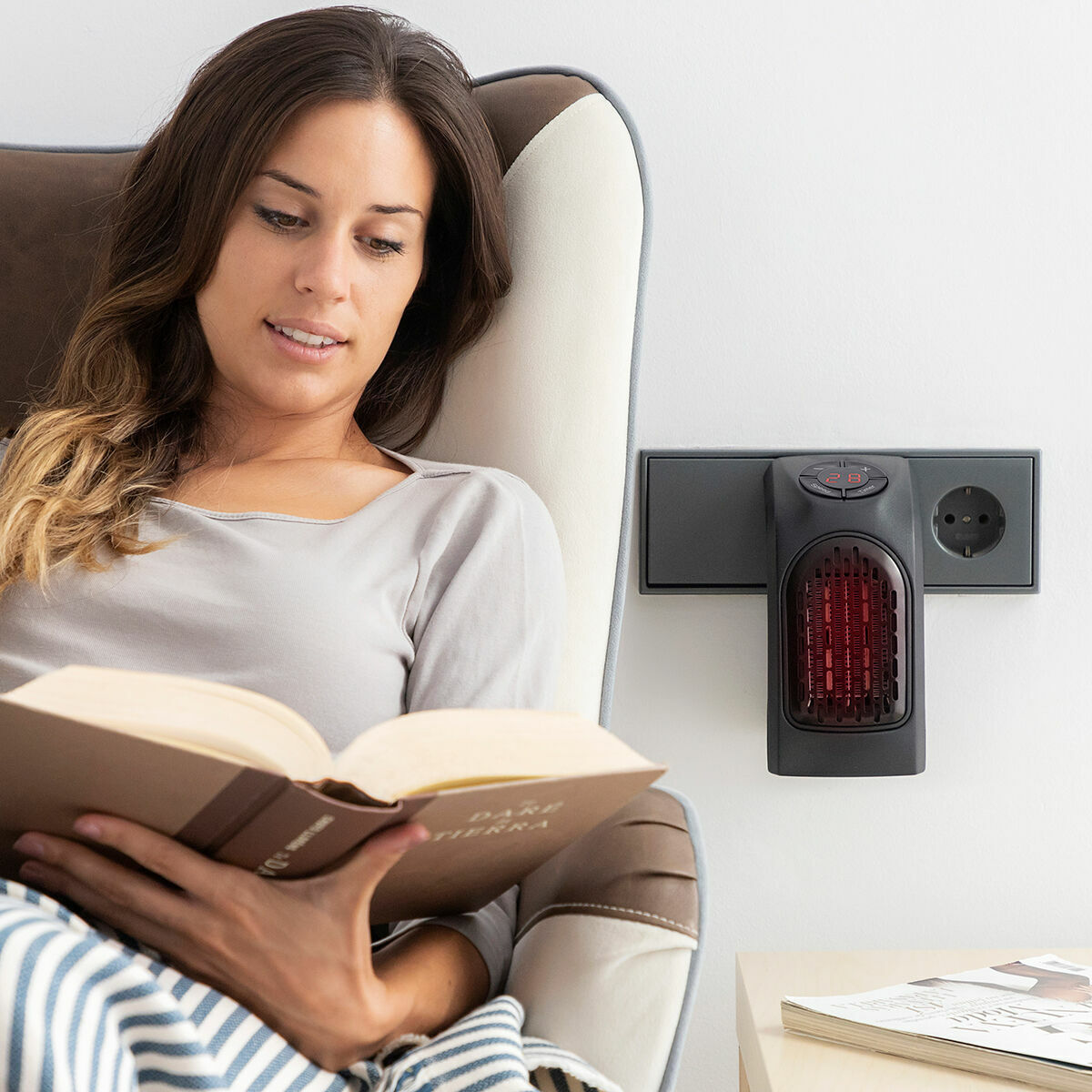 A woman is sitting comfortably and reading a book with the heater in use, indicating a relaxed and warm home environment.