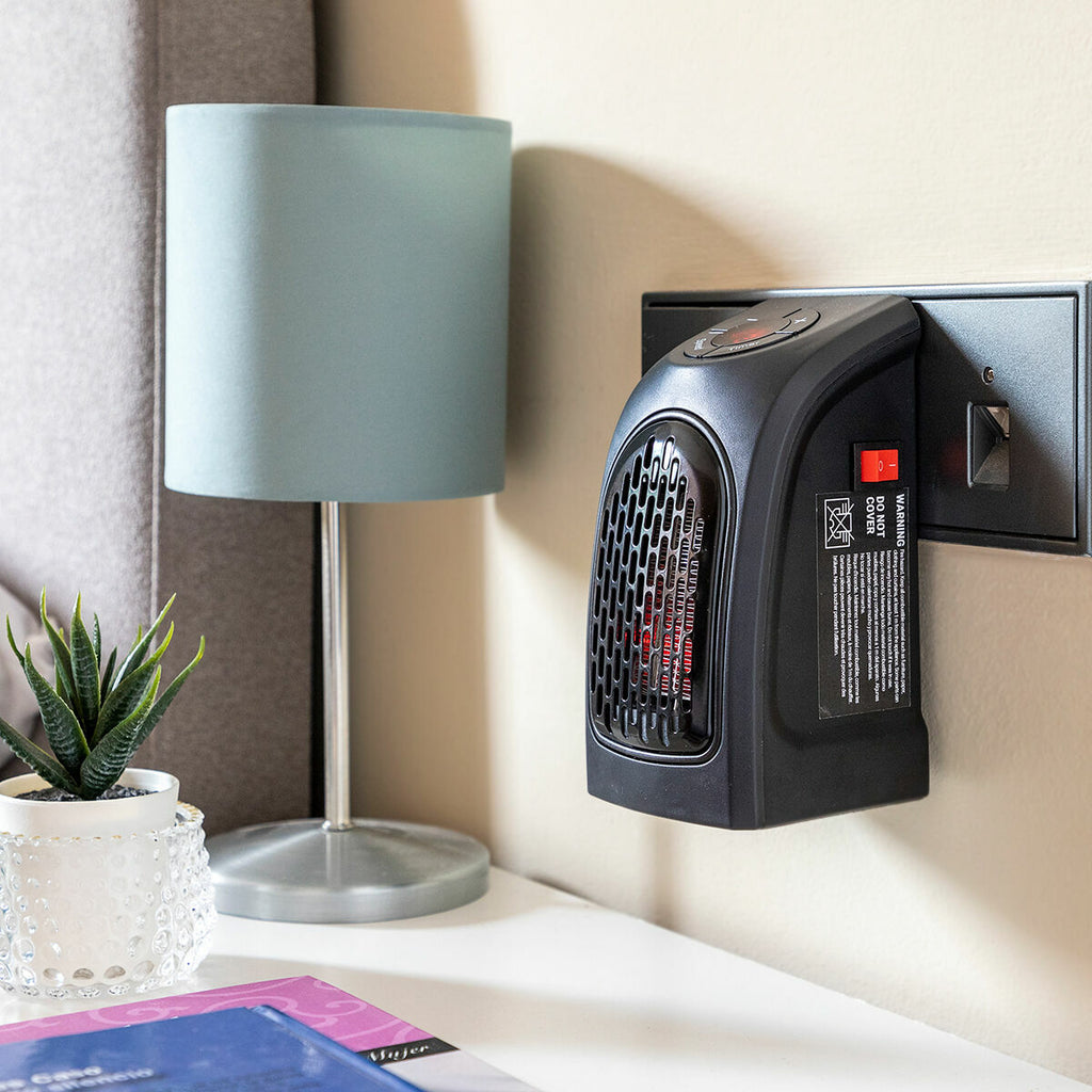 Lifestyle setting with the heater on a wall outlet near a bedside table with a lamp and plant, emphasizing its suitability for cozying bedrooms.