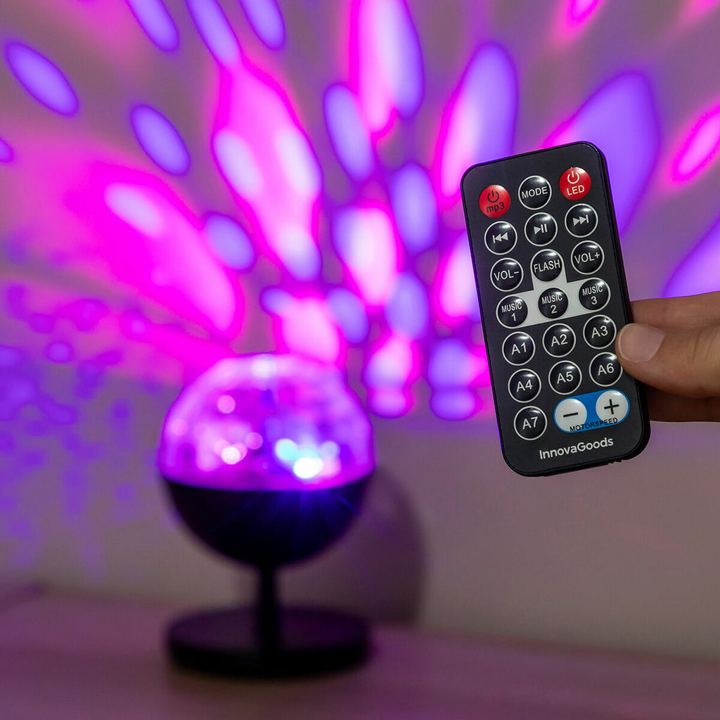 The image shows a person holding the remote control for the LED projector with an illuminating light display in the background, offering a close-up of the remote's features.