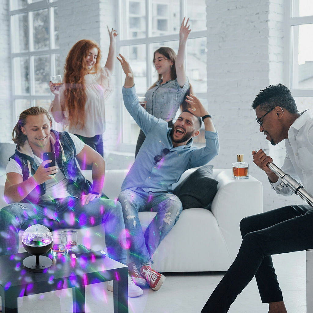 An indoor party setting with people enjoying the colorful light effects produced by the Rechargeable LED Projector with Speaker Istarlyt InnovaGoods, enhancing the mood and atmosphere.