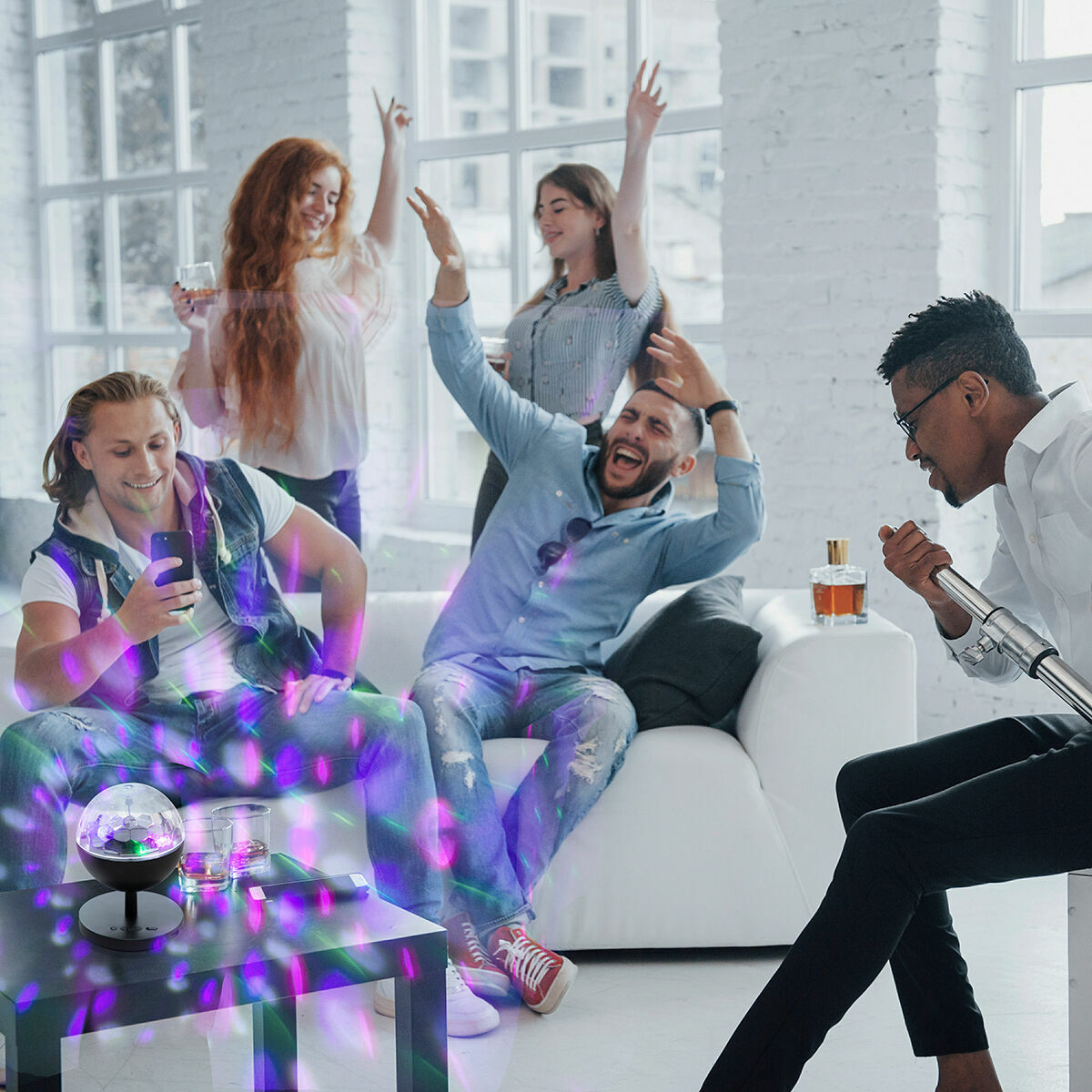 An indoor party setting with people enjoying the colorful light effects produced by the Rechargeable LED Projector with Speaker Istarlyt InnovaGoods, enhancing the mood and atmosphere.
