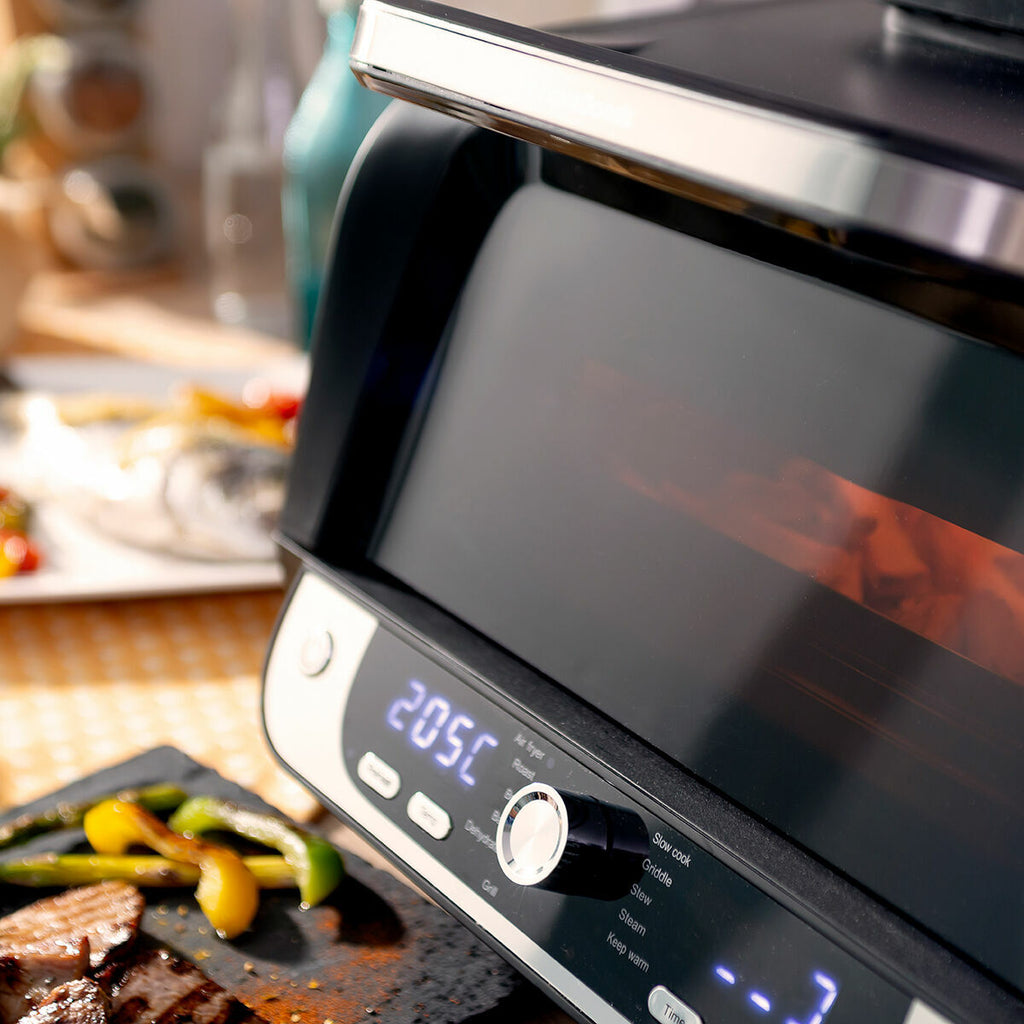 Close-up of the air fryer during operation with a focus on the digital display and surrounding food.