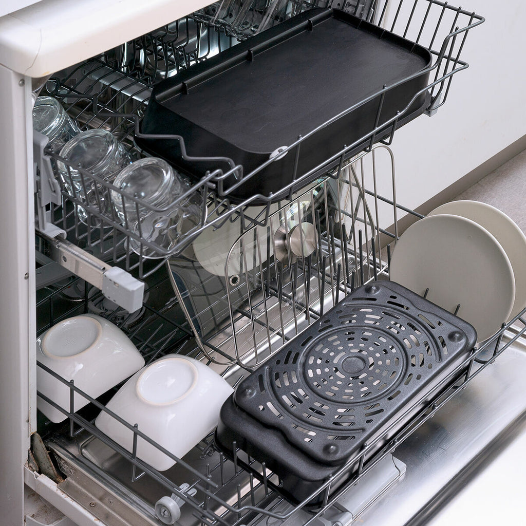 Dishwasher with trays and kitchenware inside, demonstrating the washability of accessories.