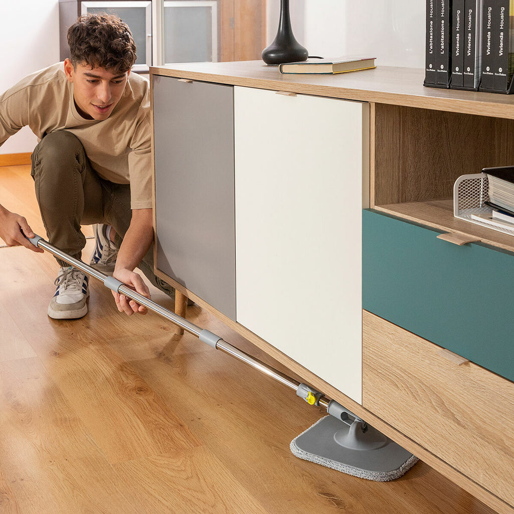 Person using the mop under furniture, highlighting flexibility and ease of use in tight spaces.