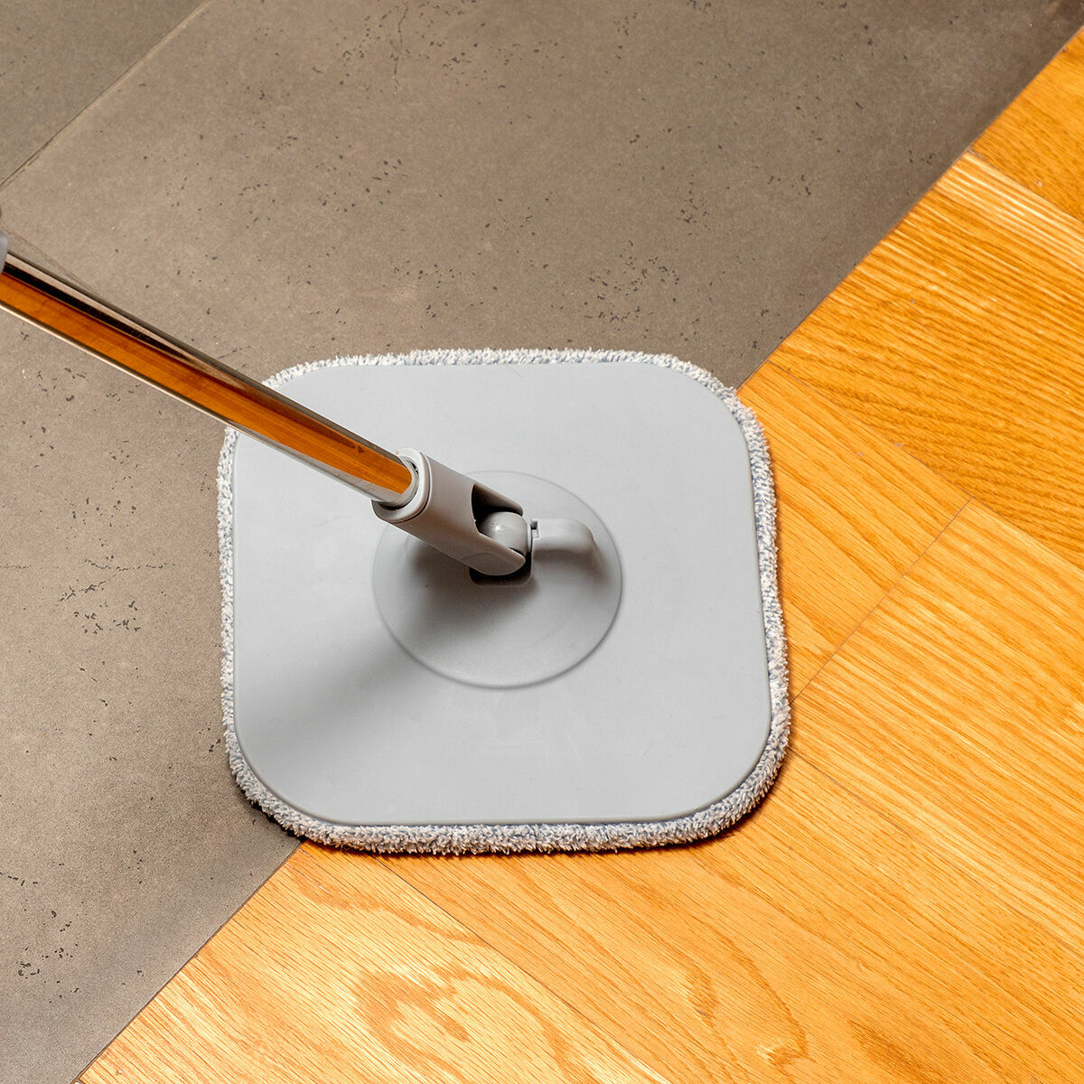 Close-up of the mop cleaning a transition between tile and wood, emphasizing cleaning ability.