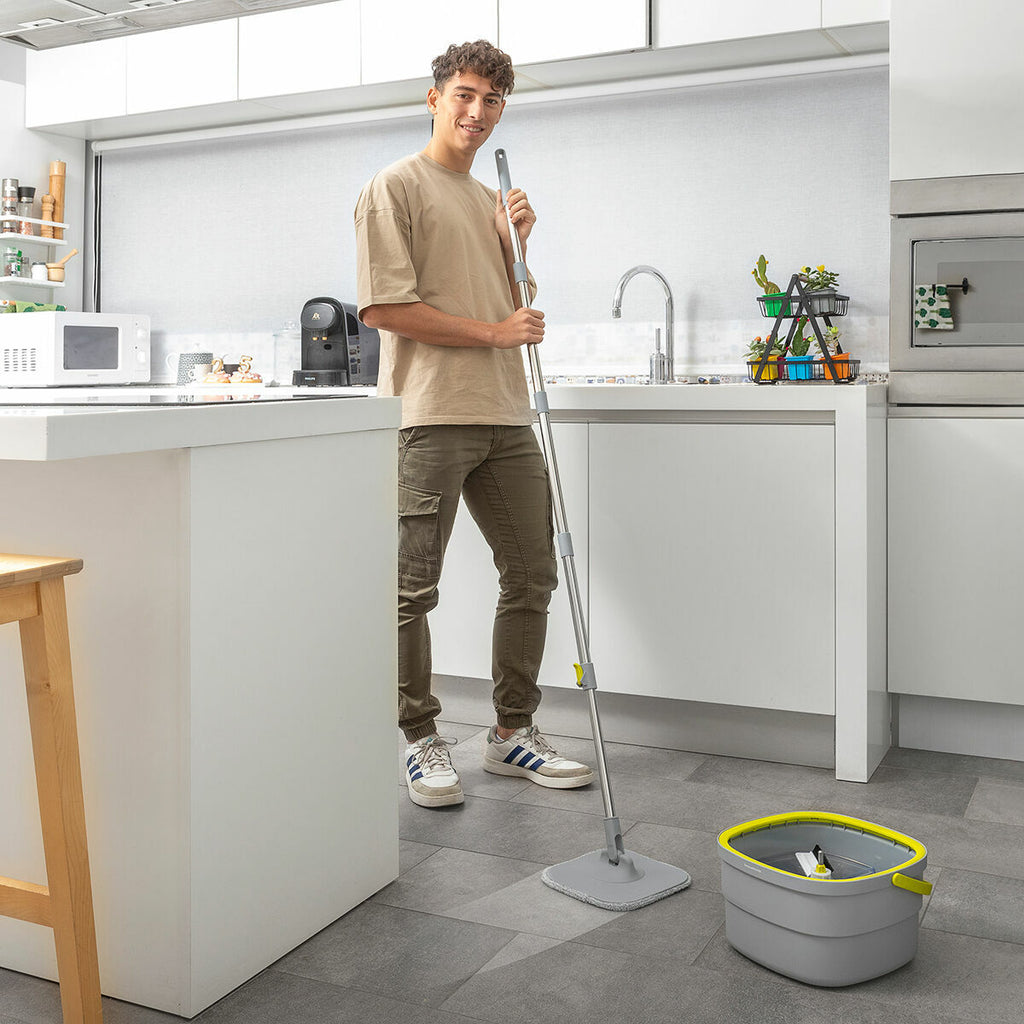 Person using the mop in a modern kitchen setting with grey and white decor and tiled floor.