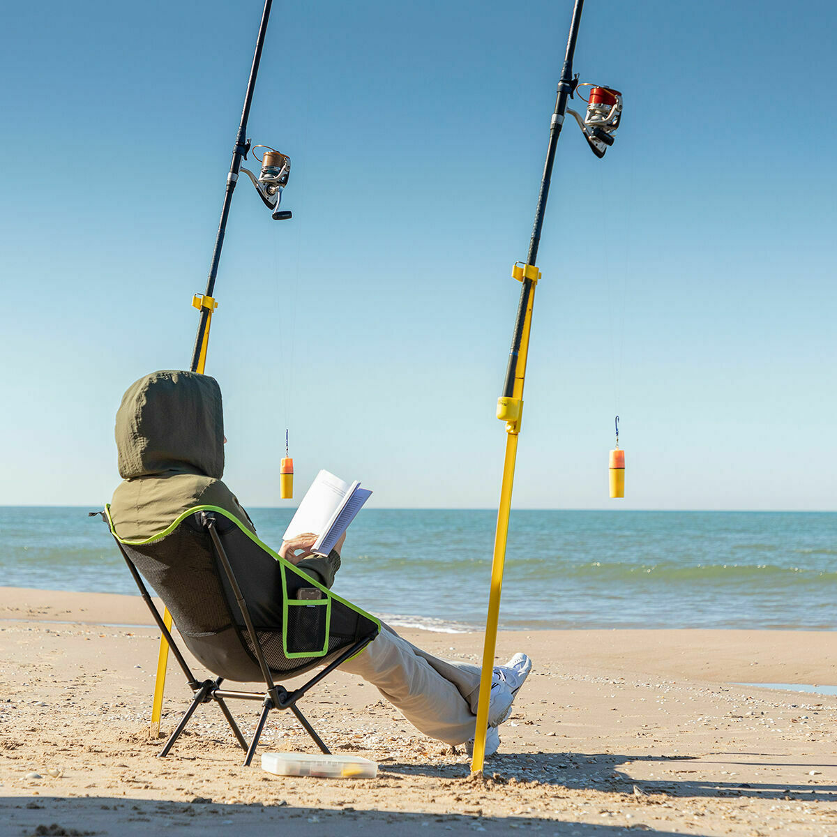 The chair being used on a beach setting by a person reading, illustrating its comfort and versatility for leisure activities. The chair's structure and design are visible, set against an ocean backdrop.