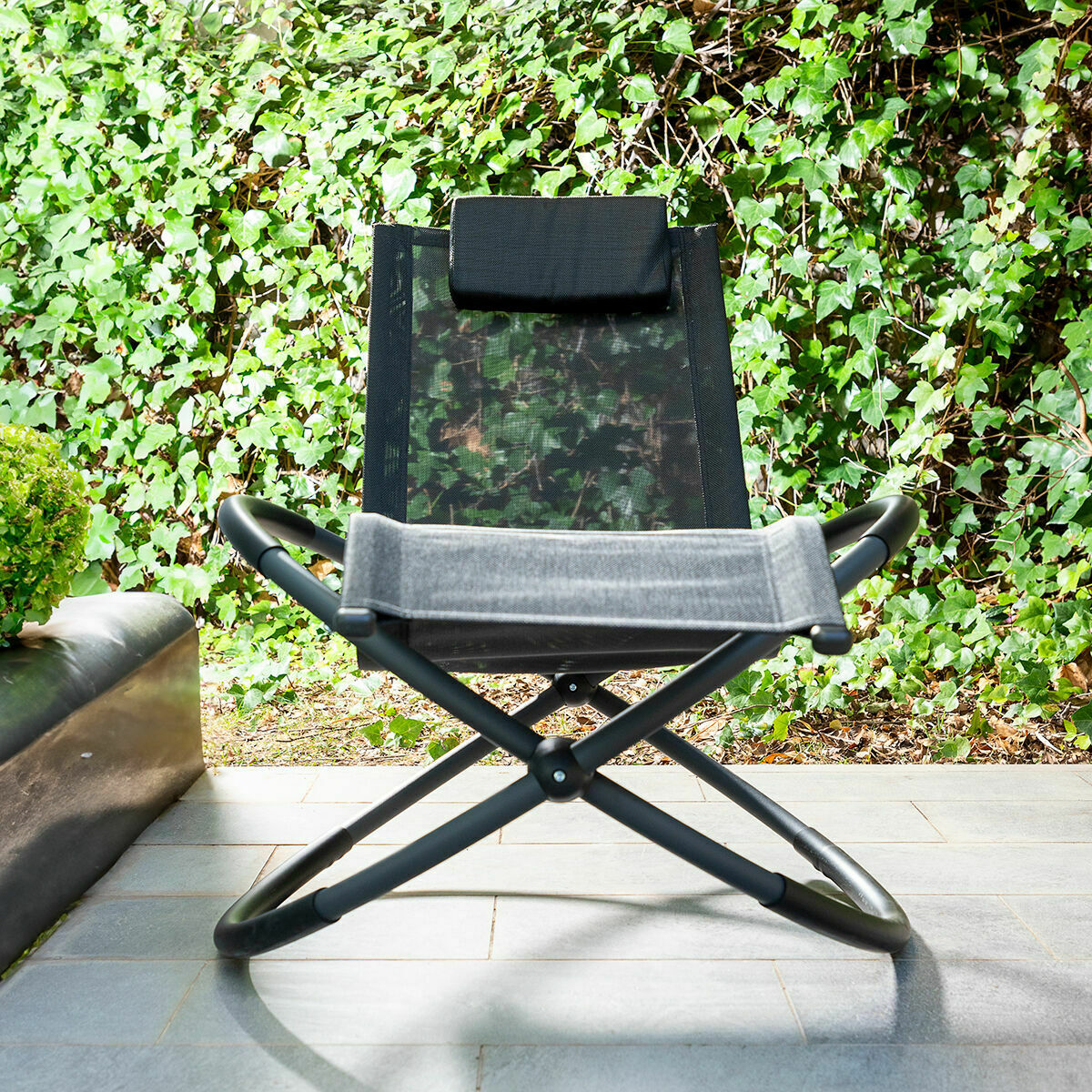 The Rockorb chair stands upright with a backdrop of lush garden greenery, demonstrating its design and structure.