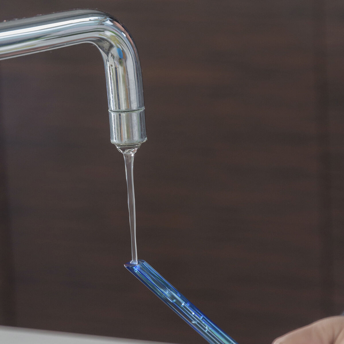 A watering globe being filled with water from a faucet, demonstrating the easy setup process.