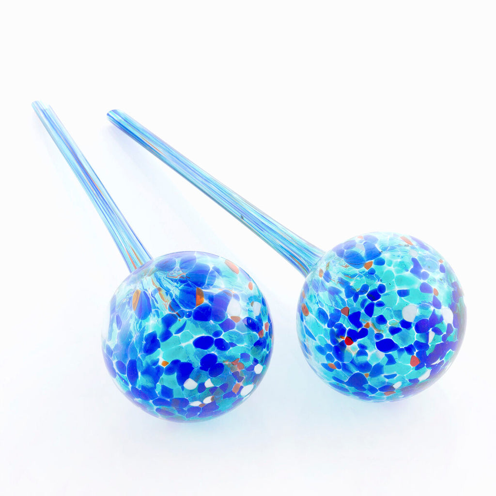 Two decorative watering globes made of glass with multicolored patterns against a plain white background.