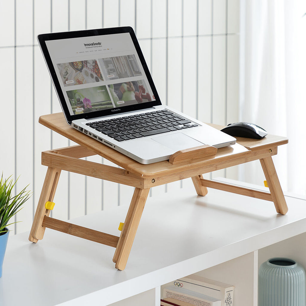 Top-down view of the table on a lap, showcasing laptop usage with a notepad and cup also on the table.