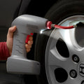 A gray InnovaGoods portable air compressor with a red trigger and a red nozzle. The device is being used to inflate a car tire, with an LED light illuminating the area.