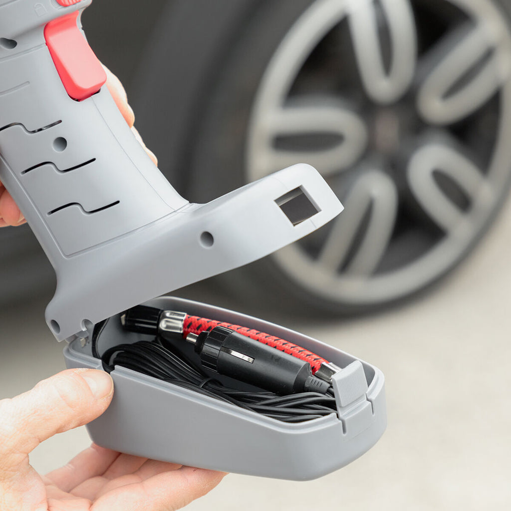The base compartment of the air compressor open to reveal storage for its hose and power cable, showing its compact and efficient design.