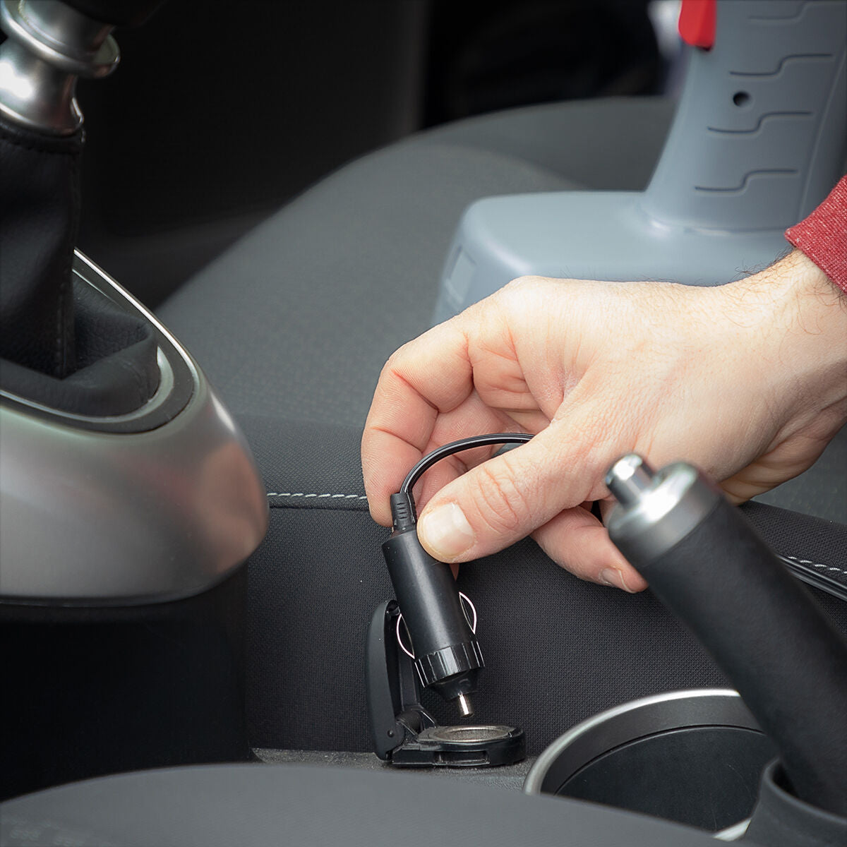 The power adapter of the air compressor being plugged into a car's power outlet, highlighting its car-friendly charging capability and ease of use in vehicles.