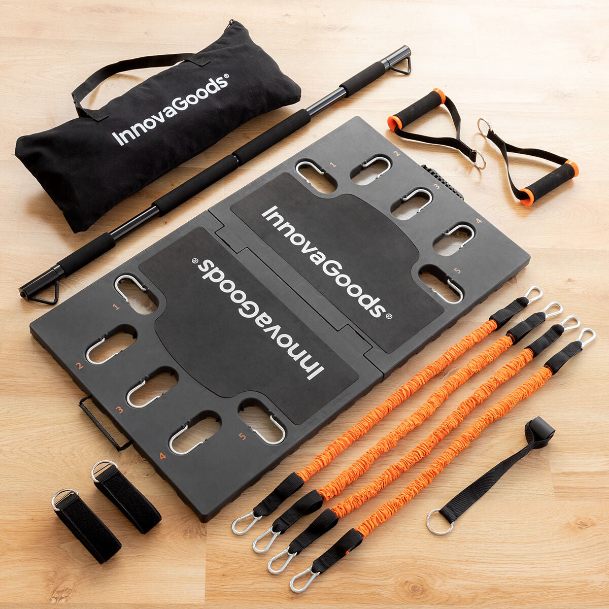 Components of the Gympak Max system laid out, including black exercise board, orange bands, bar, handles, and branded storage bag, emphasizing the total package.