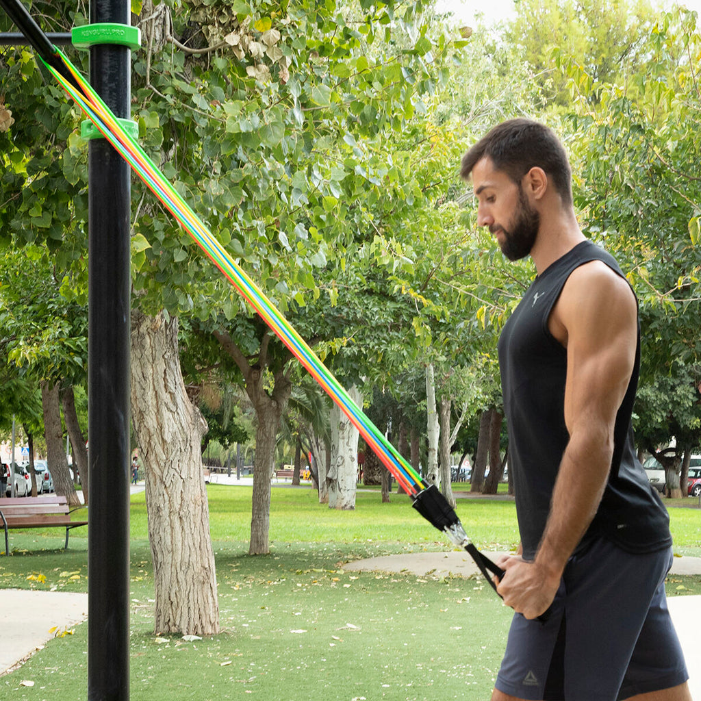 A male user doing an exercise with resistance bands outdoors in a park setting.