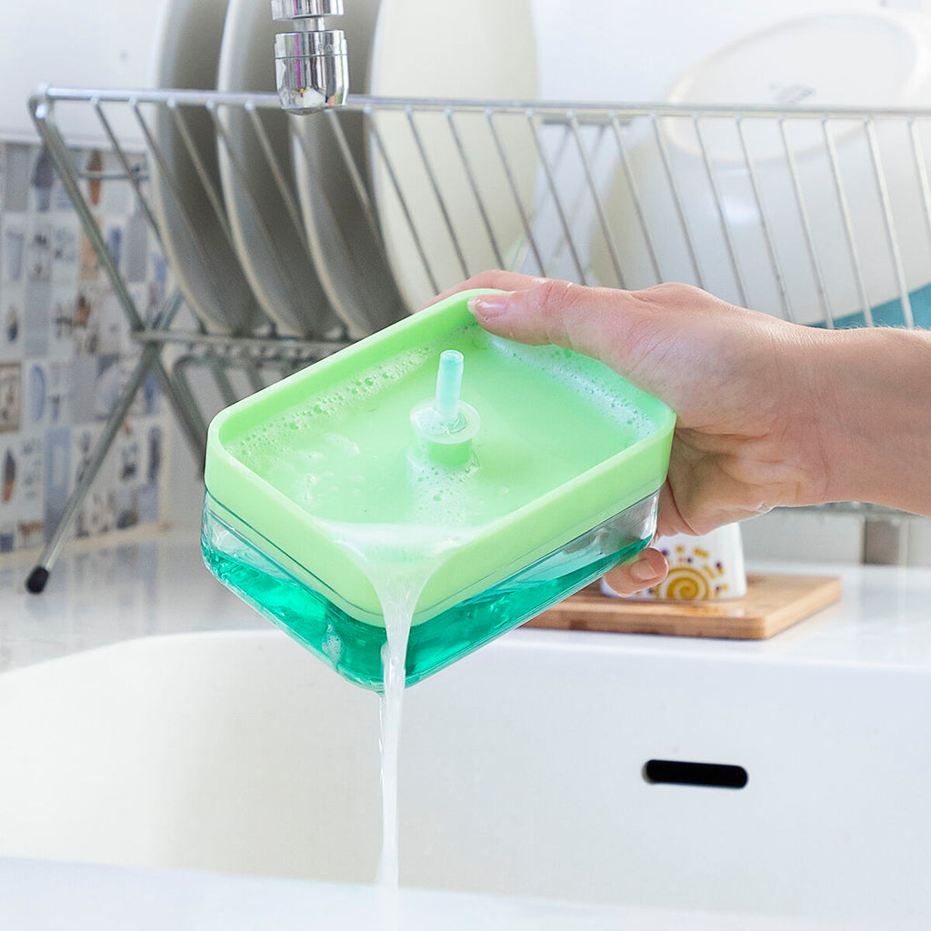A lifestyle shot demonstrating the dispensing aspect of the InnovaGoods Pushoap 2-in-1 Soap Dispenser. A hand is shown pouring out the green liquid, emphasizing its convenient refill design.