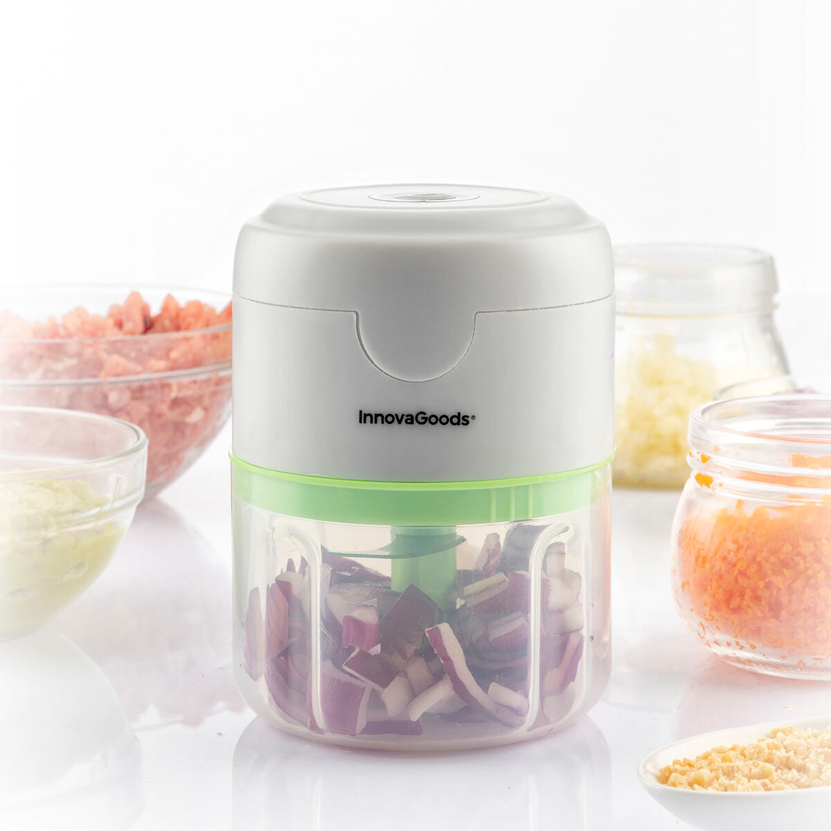A usage shot of the mini chopper with various chopped vegetables around it, emphasizing its chopping capability in a kitchen setting.
