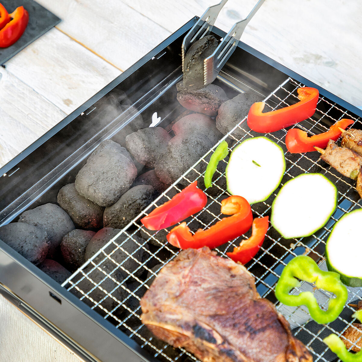 Action shot showing charcoal being placed inside the grill, conveying usability.