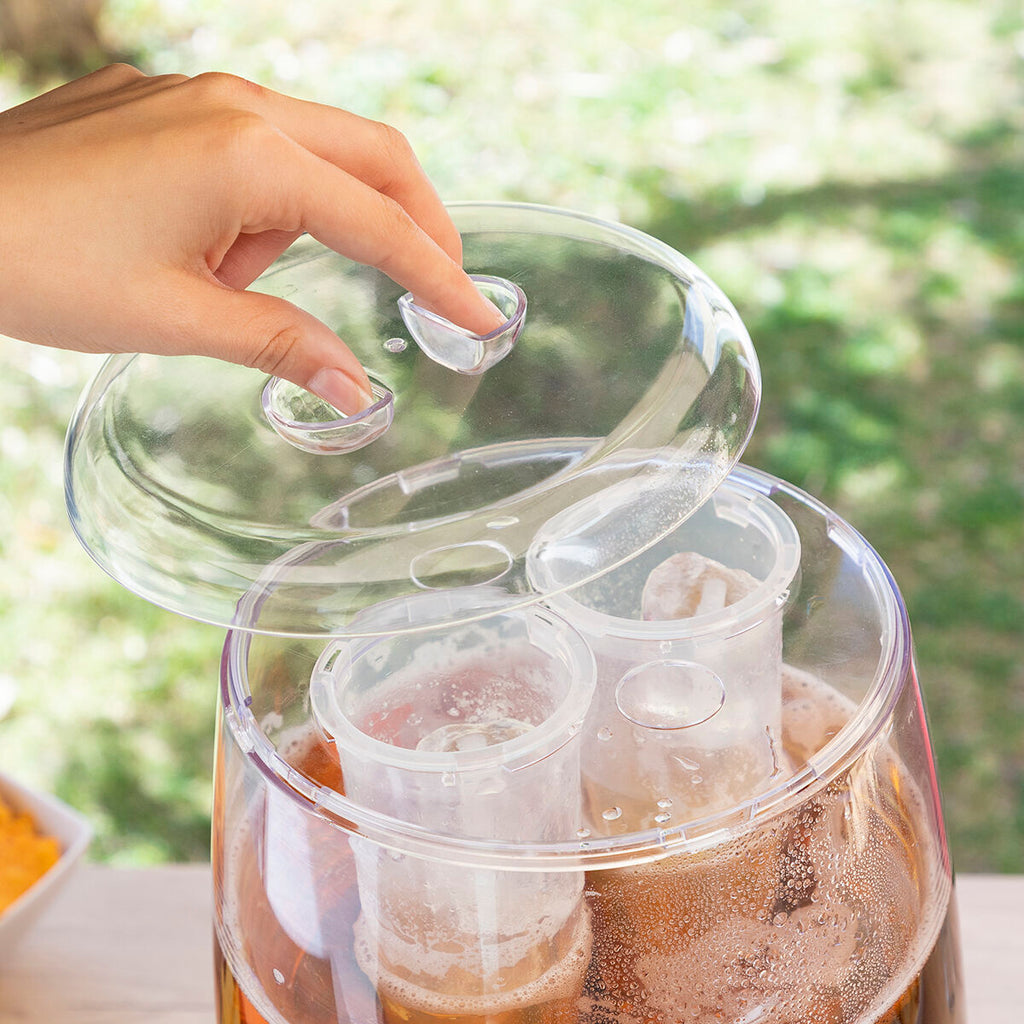A hand removing the top lid of the dispenser, showing the ice compartment interior.