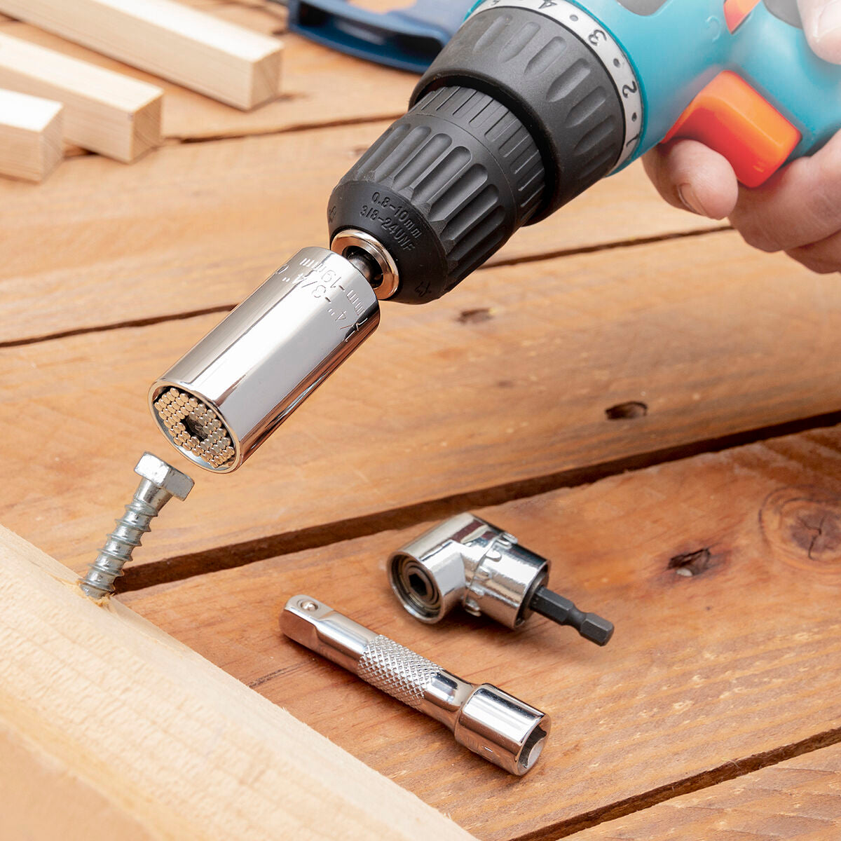 A universal socket wrench attached to a drill, shown in use on a wooden surface with screws. The chrome finish and expandable parts of the socket are visible.