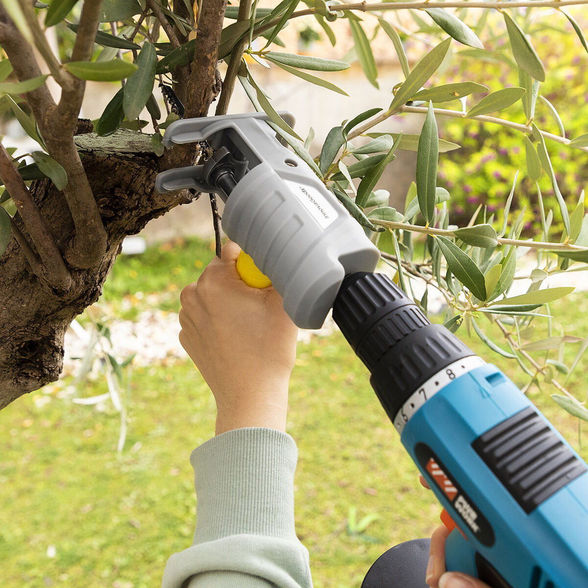 A close-up of the Jigsaw Drill Attachment in use outdoors, cutting tree branches, highlighting its versatility for garden tasks.