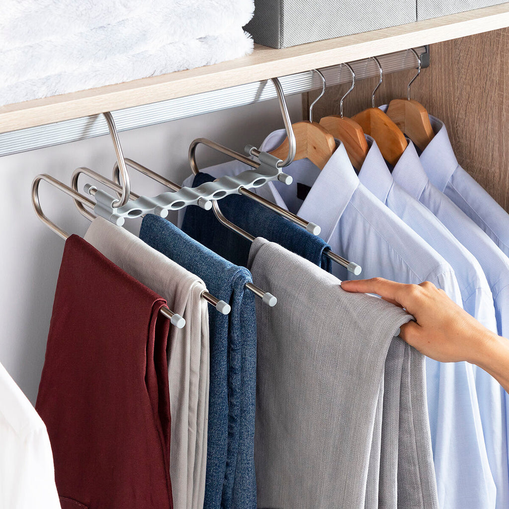 Hanger in use with hand adjusting trousers, showing ease of use within a closet setting.
