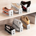 The image shows several shoe organizers in use, holding various types of shoes like sneakers and high heels. They are placed on wooden shelves, with each organizer in gray featuring an adjustable two-level design to maximize space efficiency.