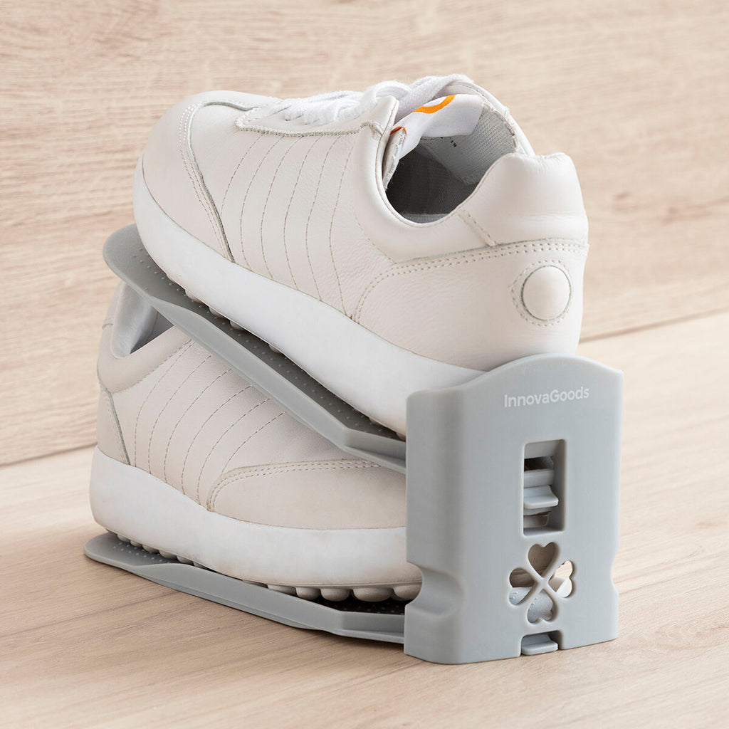 A casual setting image with a pair of white sneakers fitting snugly in the shoe organizer. The organizer's gray color contrasts neatly with the wooden backdrop.
