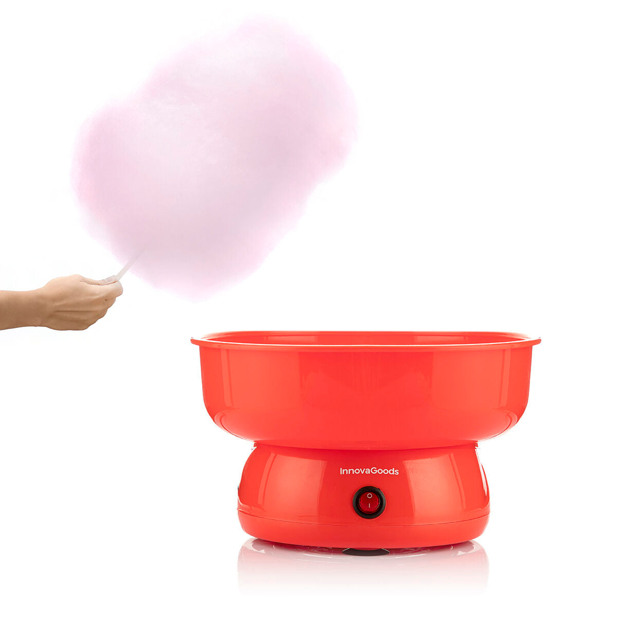 The machine in use with cotton candy being made. A hand holds a stick with freshly spun pink cotton candy at the side of the machine.