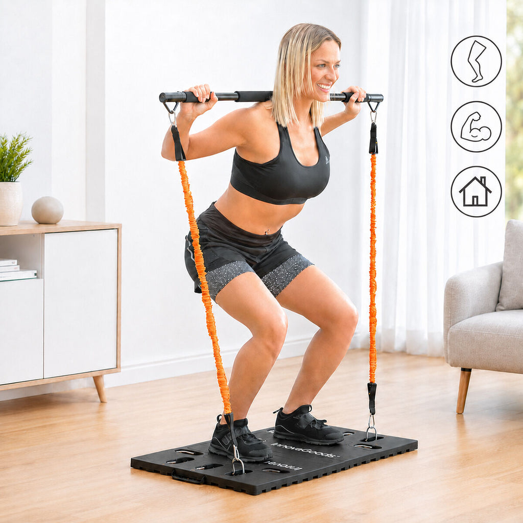 A woman is using the portable training system, performing a squat with the bar on her shoulders, attached to orange elastic bands on a black platform. The setting is indoors.