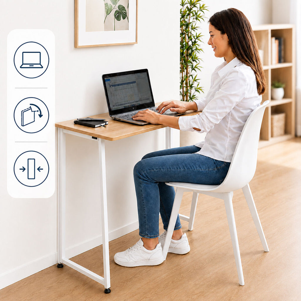 A person is using a Folding desk Dolenkaf InnovaGoods placed against a white wall. The desk has a wooden surface with white metal legs. A folded laptop and smartphone are on the desk. Icons illustrating various functions of the desk are displayed vertically on the left.