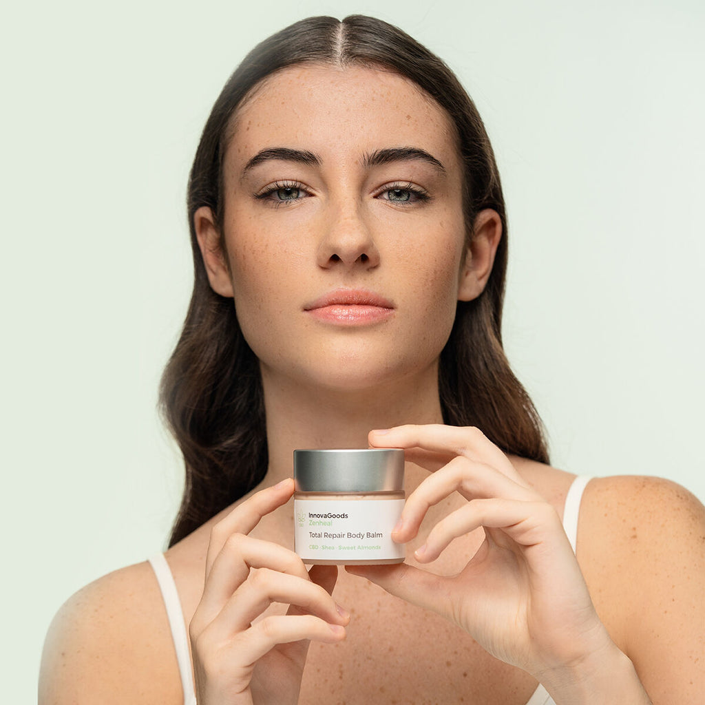 The model is holding the closed balm jar towards the camera, prominently showcasing the product. She has a serene expression, which adds an element of calm and trust to the product image.