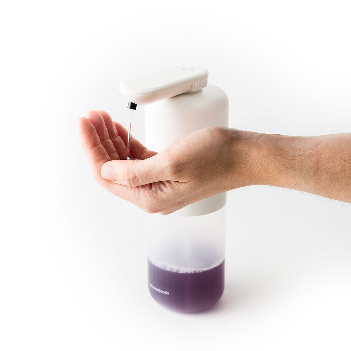 A hand using the dispenser, showcasing its use and the dispensing of soap. The design features a white top with a protruding nozzle and clear bottom containing purple soap.
