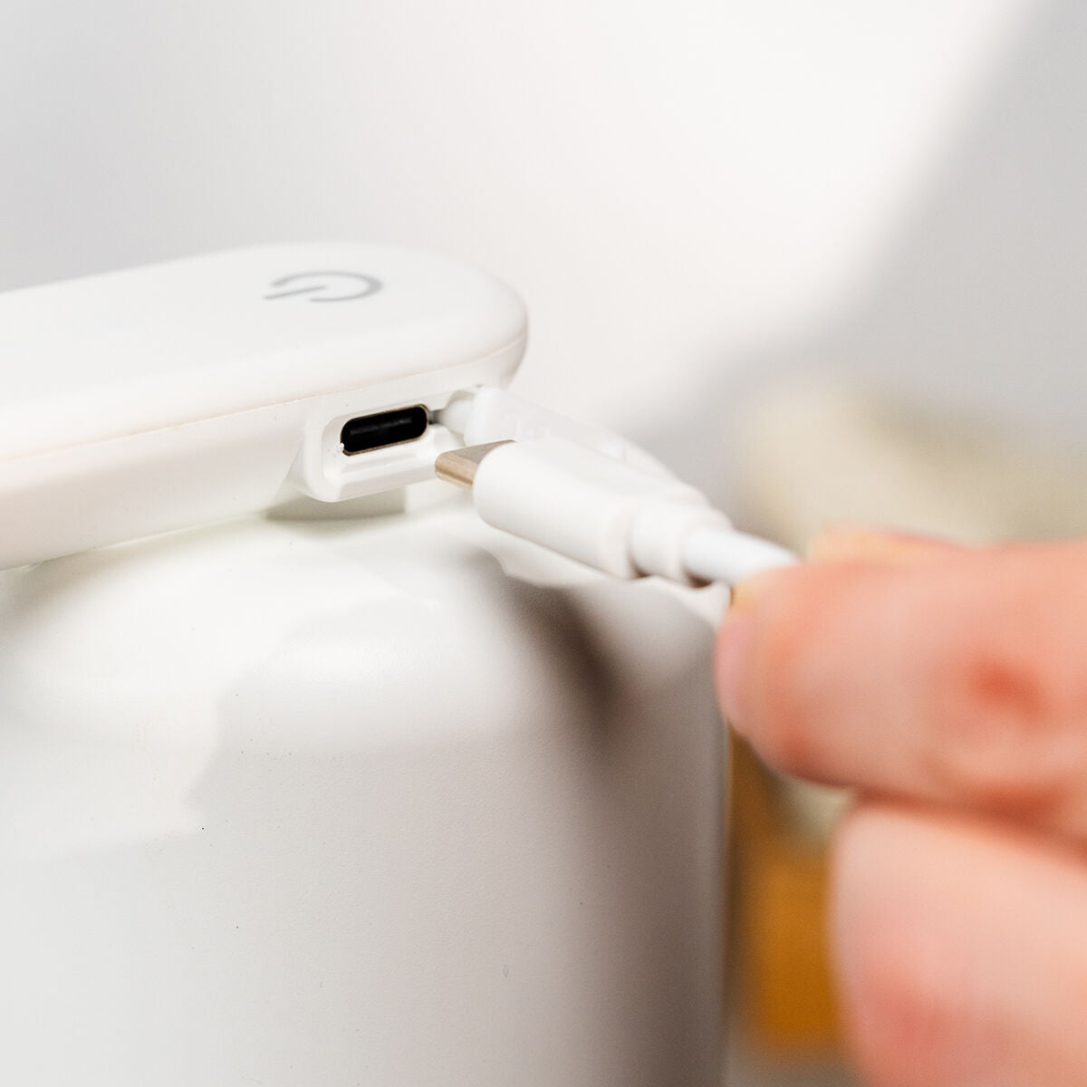 Close-up of USB-C charging port on the dispenser, with cable being inserted, highlighting its rechargeable feature.