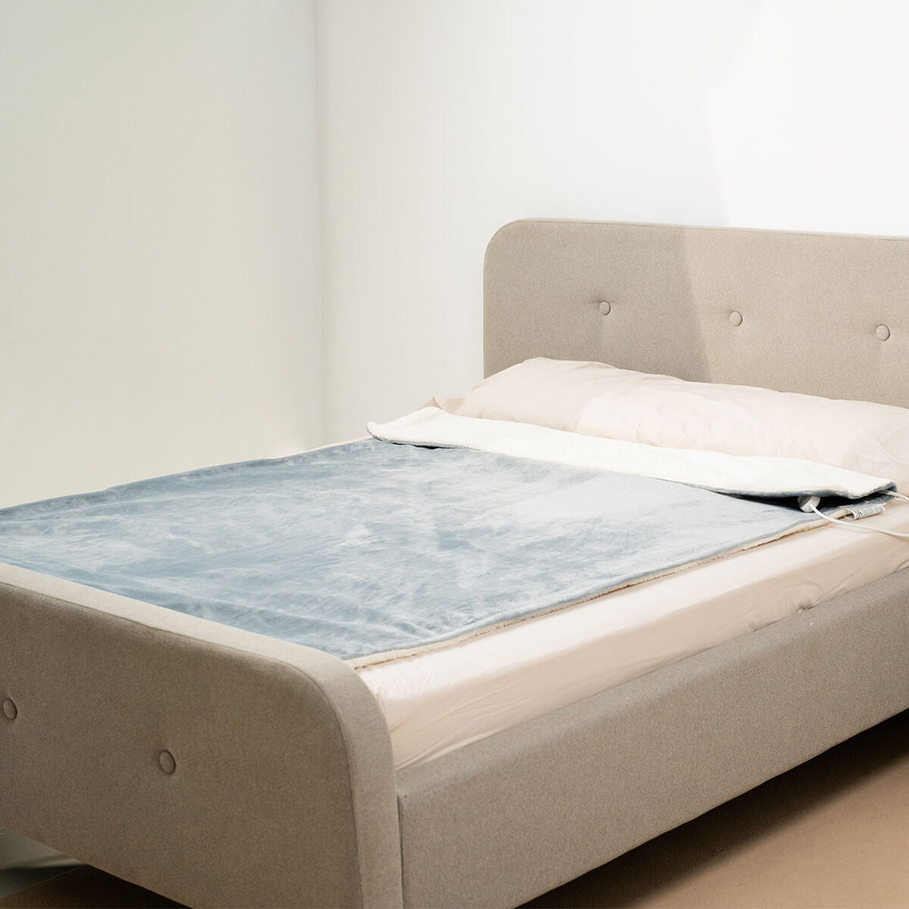 Electric blanket spread out on a bed.