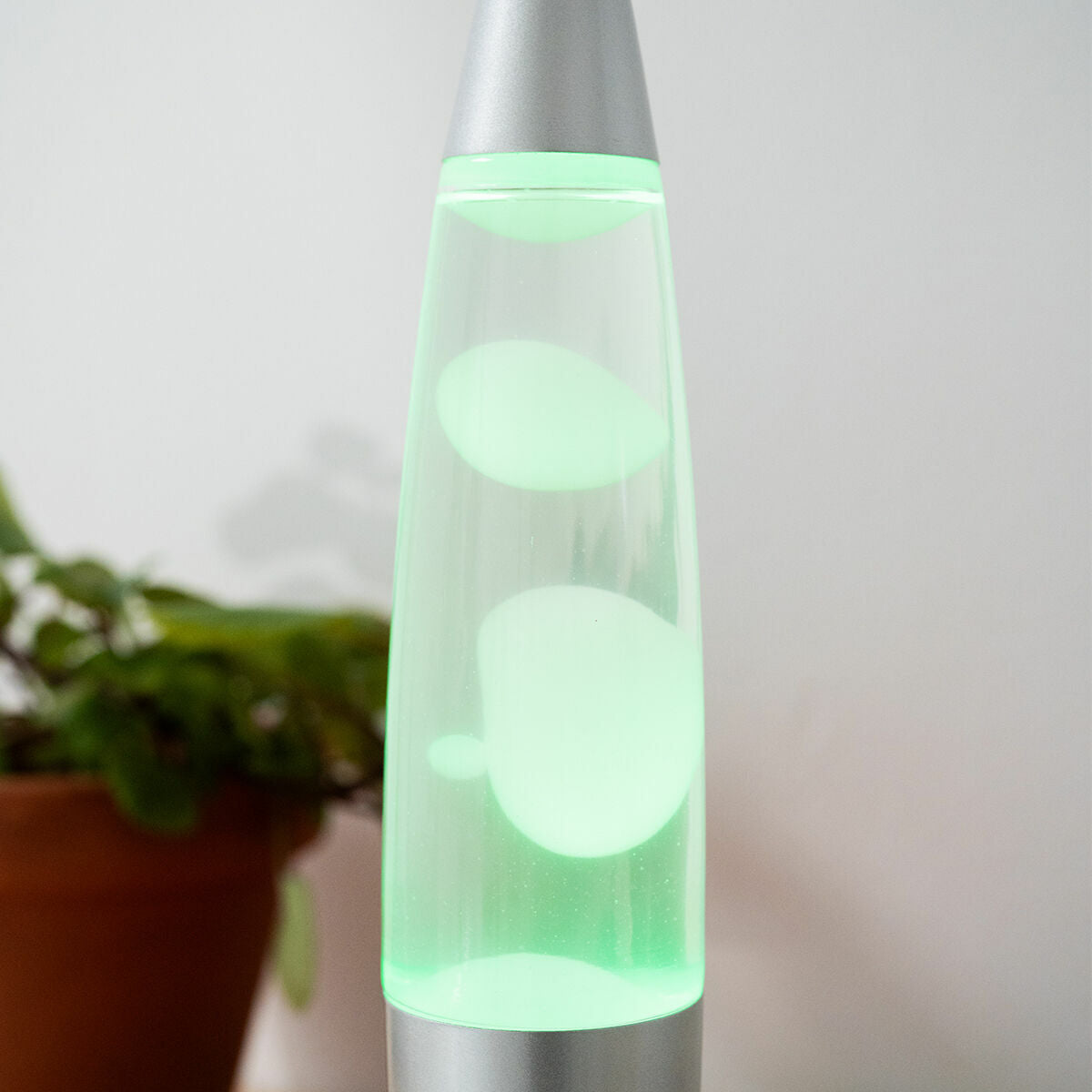 Close-up of the lamp with green LED light near a plant, showcasing its aesthetic features.