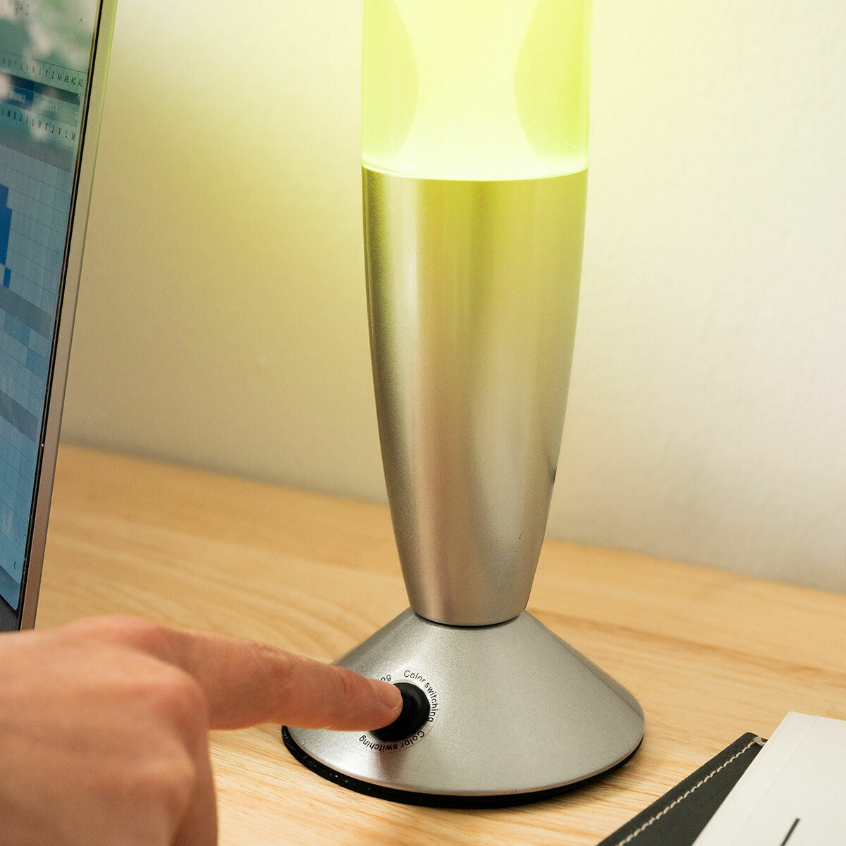 A hand pressing the button on the lamp's base, showing the color switching functionality.