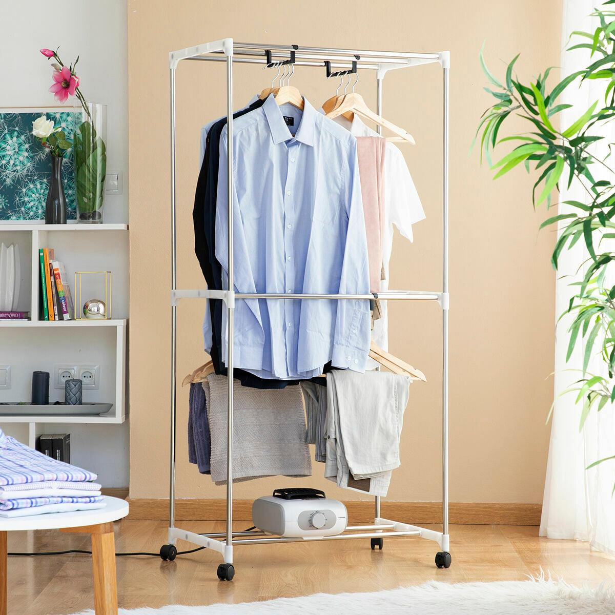 The dryer is shown without the cover, focusing on the interior arrangement of clothes hanging neatly on hangers. It’s set in a cozy home environment that includes furniture and decor, hinting at the product’s practical integration into daily living spaces.