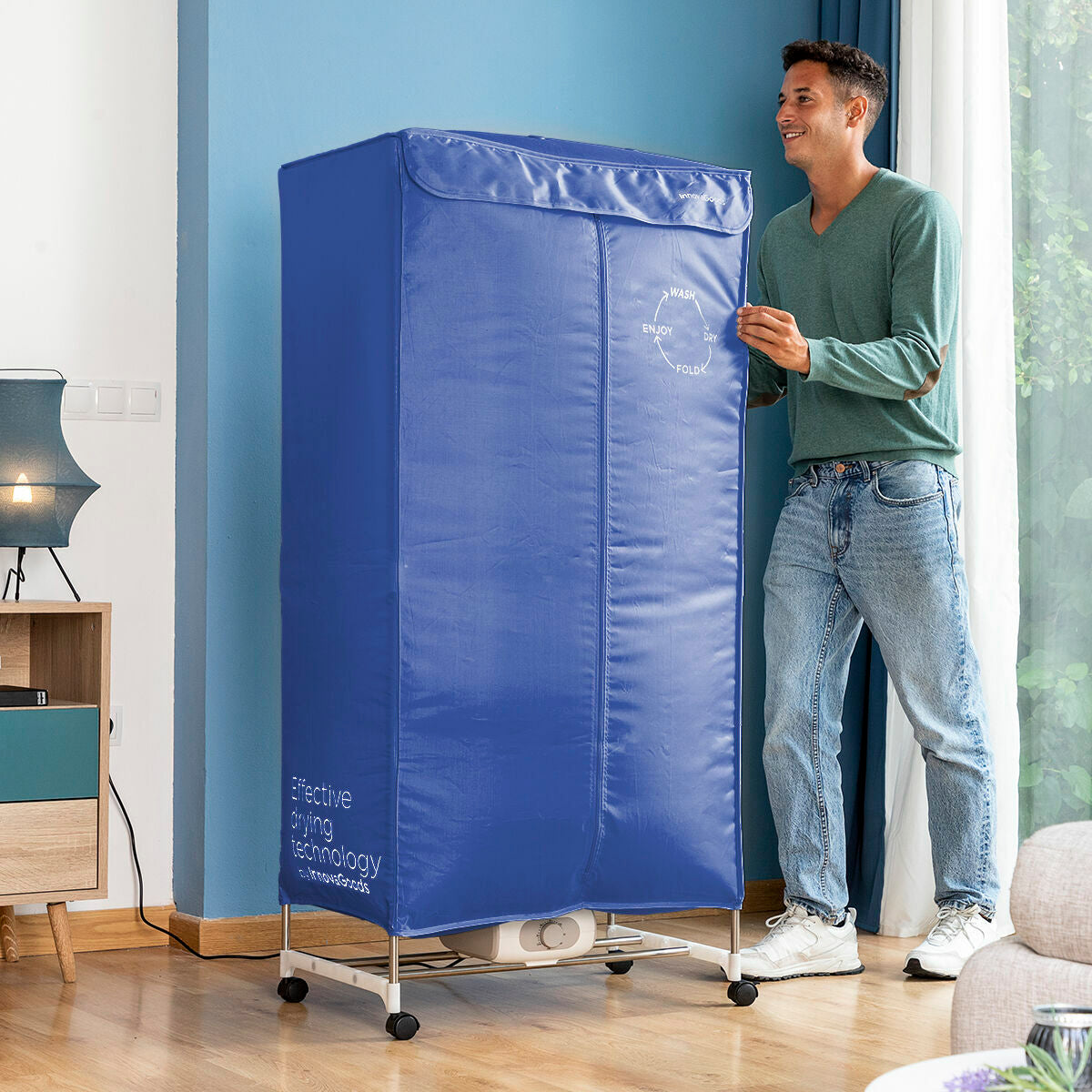 A person interacting with the dryer, which is fully assembled with the blue cover standing upright. The individual is adjusting or zipping the cover, providing scale and interaction.