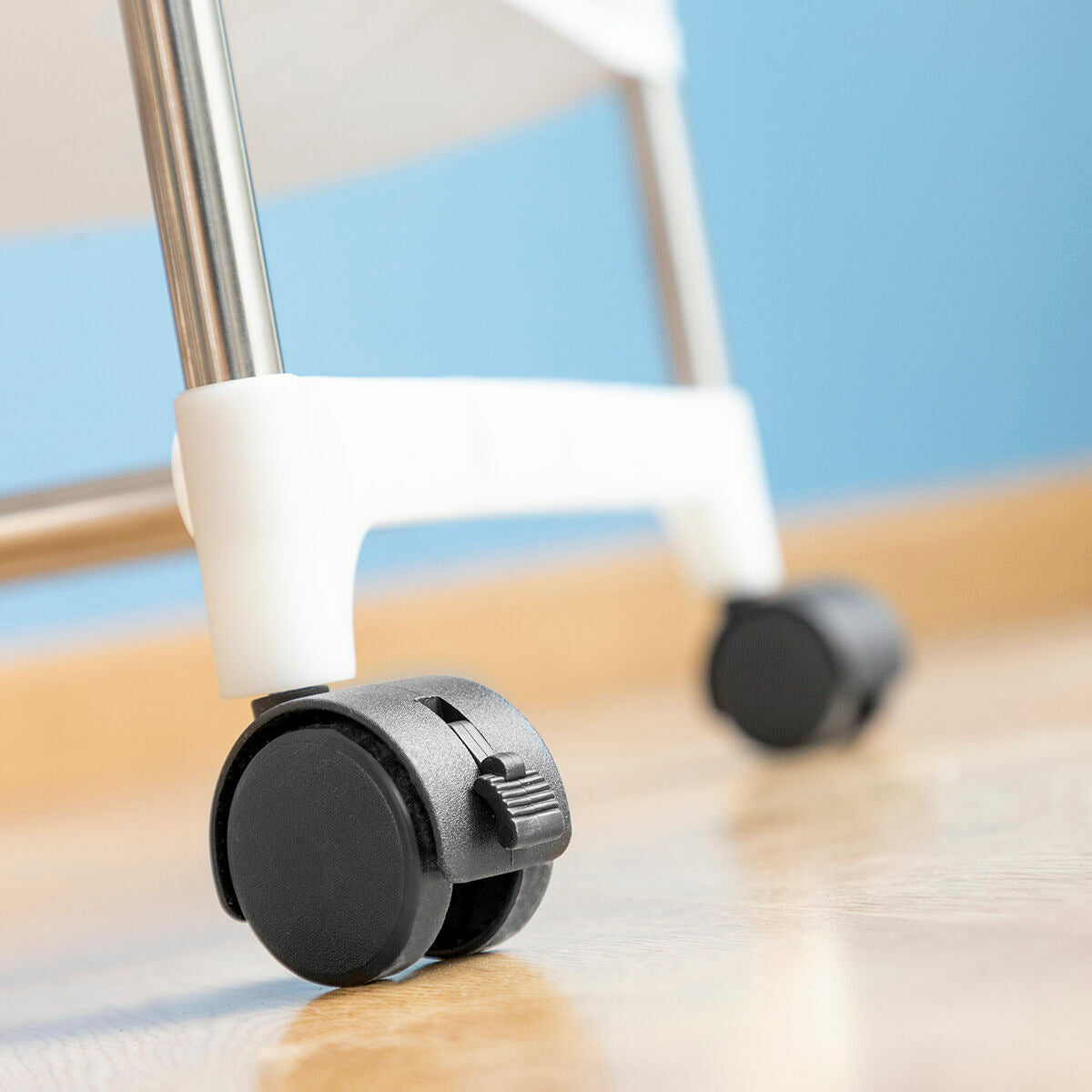 Close-up of one of the wheels on the metal frame, highlighting the mobility feature of the dryer. The black and white wheel sits against a smooth wooden floor.