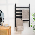 The product in a bathroom setting, mounted on the wall with towels hanging, against a white wall with natural wood furnishings.
