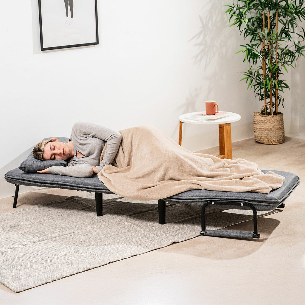 A woman lounging on the sofa in a reclined position, wearing headphones and appearing relaxed.