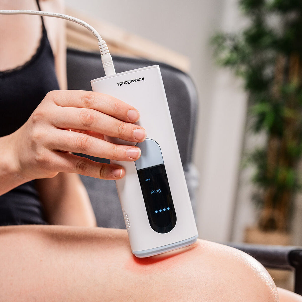 A close-up image of a woman using the Pulsed Light Hair Remover on her leg while seated, highlighting detailed usage.